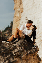 Wall Mural - Happy couple are sitting and kissing on the stone mountain. Panorama view from the peak.