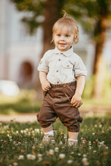 Wall Mural - A small blond boy dressed in a vintage jumpsuit in a field at sunset