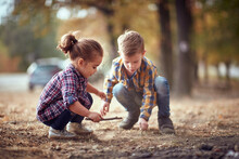 Little Brother And Sister Playing In The Dirt In The Forest