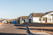 A row of new houses, being constructed during Arizona building boom, stands in early morning light on a dirt lot, horizontal view.