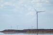 © Kathrine Andi - Wind generators energy farm on sea coast with reflection. Epic cloudy sky cloudscape. Energy turbines power