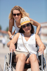 invalid girl on the wheelchair with friend outdoors