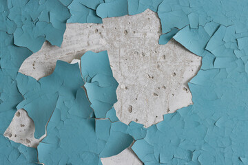 Peeling paint on the wall. Old concrete wall with cracked flaking paint. Weathered rough painted surface with patterns of cracks and peeling. High resolution texture for background and design. Closeup