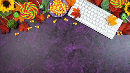 Wall Mural - Happy Halloween Trick or Treat theme desktop with candy and lollipops, autumn leaves on stylish purple textured background. Top view blog hero header creative flat lay. Negative copy space.