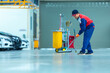 © tong2530 - Asian worker in car mechanic repair service center cleaning using mops to roll water from the epoxy floor. Mops in the car repair service center..