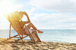 © New Africa - Woman relaxing on deck chair at sandy beach. Summer vacation