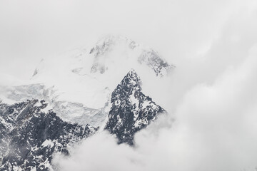  Atmospheric minimalist alpine landscape with massive hanging glacier on snowy mountain peak. Big balcony serac on glacial edge. Low clouds among snowbound mountains. Majestic scenery on high altitude.