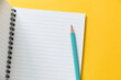 © iamtui7 - top view of empty open lined notebook with blue color pencil on yellow background with copy space, flat lay