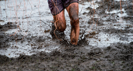 Mud race runner, man running in mud. Runners during extreme obstacle races. Active life and sport concept..