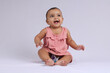 © Ojas - cute Indian cheerful baby sitting and smiling over white.