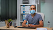 © DC Studio - Worker wearing protective face mask and talking on camera about company problems during coronavirus. Pov of entrepreneur working in new normal workplace having online meeting, with remotely team
