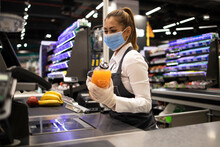 Working During Covid-19 Pandemic. Cashier At Supermarket Wearing Mask And Gloves Fully Protected Against Corona Virus.