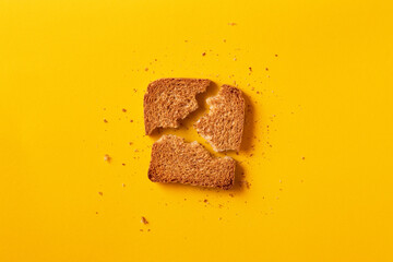 Wall Mural - Single toast bread broken on a yellow background viewed from above. Top view. Whole wheat brown bread