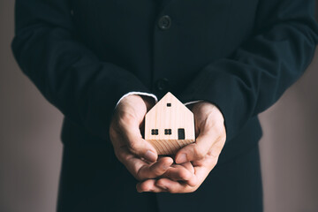 Business realtor man holding home model for investment