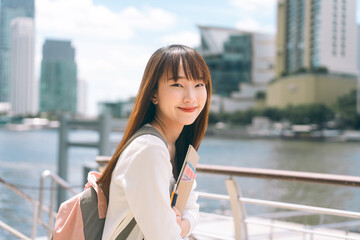 Wall Mural - Portrait of happy young adult asian college student woman with notebook.