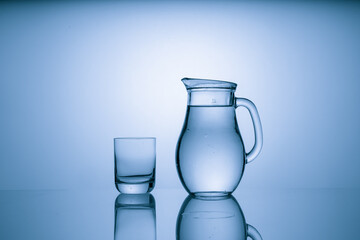 Pitcher with drinking water and a glass with a drink, blue tone