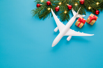 Wall Mural - Christmas travel planning. Traveling as gift. White blank model of passenger plane and gift box on blue background. Top view or flat lay. Copy Space.