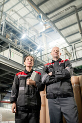 Poster - Contemporary male and female engineers standing against warehouse environment