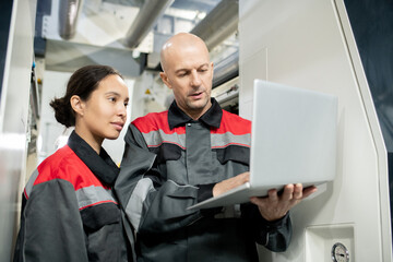 Poster - Confident bald mature foreman in workwear holding laptop during presentation