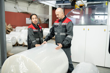 Aufkleber - Young female factory worker and her male colleague standing by huge packed roll