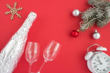 Christmas composition with bottle of champagne in silver foil and two glasses  on the red background