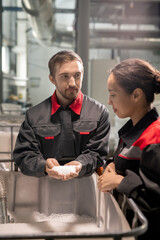 Poster - Two young quality control managers discussing characteristics of raw materials