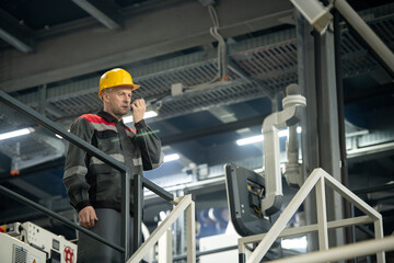 Poster - Confident mature foreman with hardhat on head and walkie talkie by his mouth
