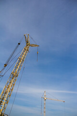 Poster - Construction crane on a background of blue sky. Equipment for lifting heavy loads on a construction site.