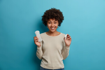 Canvas Print - Hygiene protection and womens health concept. Smiling glad Afro American woman holds tampon sanitary napkin demonstrates absorbents for critical days. Happy young female with intimate products