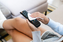 Asian Woman Hands Cleaning The Tv Remote Control With Disinfectant Wet Wipes. Prevention Of Bacteria And Covid-19 Virus Spreading Concept.