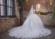 bride in a wedding dress with a long train and a bouquet in an old hall with chandeliers