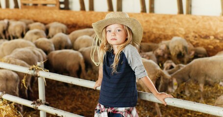 portrait of caucasian blonde pretty girl with fair hair standing at fence in stable and smiling to c