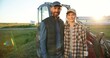 © VAKSMANV - Portrait Caucasian happy couple of married farmers standing in hugs at tractor, looking at each other and smiling to camera. Outdoor. Man hugging woman in field. Agriculture concept. Wife and husband.