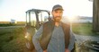 © VAKSMANV - Portrait of young Caucasian handsome happy man farmer standing in field and smiling to camera. Big tractor on background. Cheerful male worker in agricultural farm. Sunlight. Agriculture farming.