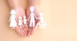 hands holding paper Cutout of different family members being together.