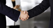 © cameravit - Unknown businesspeople are shaking their hands after signing a contract, while standing together in a modern office, close-up. Business communication, handshake, and marketing concept