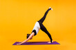 © Яна Айбазова - woman yogi performs asana Adho Mukha Shvanasana on a purple Mat on an orange background