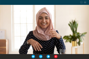 Close up headshot screen view of smiling Indian woman in hijab have webcam digital virtual conference on computer online. Happy ethnic female talk speak on video call with client or customer.