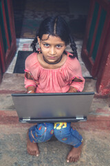 Wall Mural - Indian village girl operating laptop computer system seating at home corridor