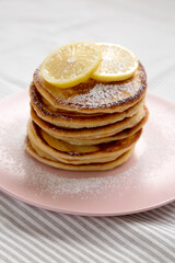 Wall Mural - Homemade Lemon Ricotta Pancakes on a pink plate, low angle view. Close-up.