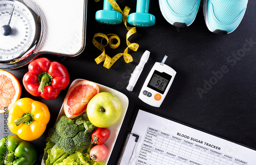 World diabetes day, Healthcare concept. Healthy food including fresh fruits, vegetables, weight scale, sports shoes, dumbells, measure tape and diabetic measurement set on black background.