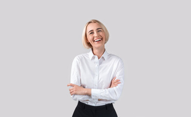 Attractive female businesswoman in formal clothes laughing on light grey studio background