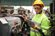 © torsakh - A Engineer woman using tablet or computer for inspect or checking or adjust or operate control the machine in workshop factory, the technician repair or maintenance part or equipment