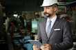 © torsakh - A smart professional business manager wear suit is working or inspect and radio to ordering in factory or production line, smart leader or entrepreneurship concept