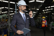 © torsakh - A smart professional business manager wear suit is working or inspect and radio to ordering in factory or production line, smart leader or entrepreneurship concept
