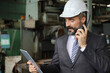 © torsakh - A smart professional business manager wear suit is working or inspect and radio to ordering in factory or production line, smart leader or entrepreneurship concept
