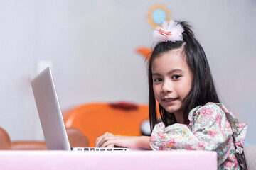 Happy and smile Asean girl using laptop computer to study online e-learning from living room decorate party holiday at home