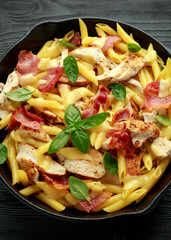 Wall Mural - Chicken, bacon Penne pasta with cheese and basil in iron cast. healthy food.