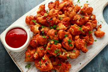 Vegan cauliflower buffalo wings on white wooden board