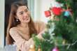 © chinnarach - close up young asian woman decorating on pine tree in living room at home for merry Christmas and happy new year festival season concept